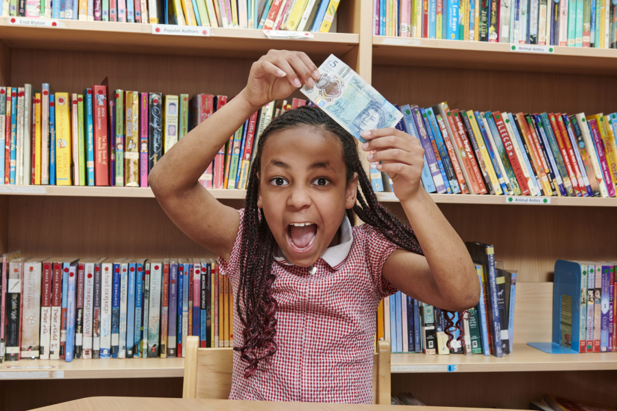 young person holding a £5 note